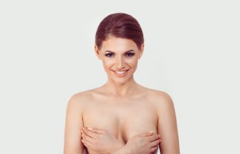 Smiling woman covering her breasts with her hands.